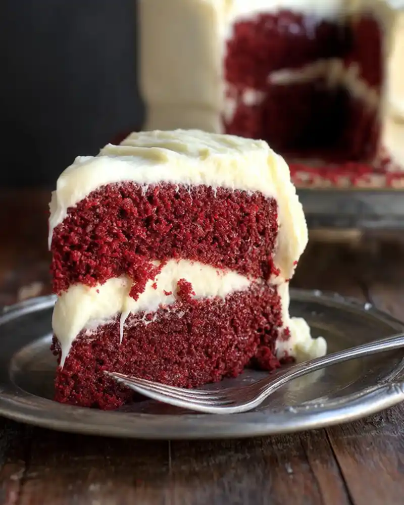 Gluten free red velvet cake slice with cream cheese frosting on a plate.