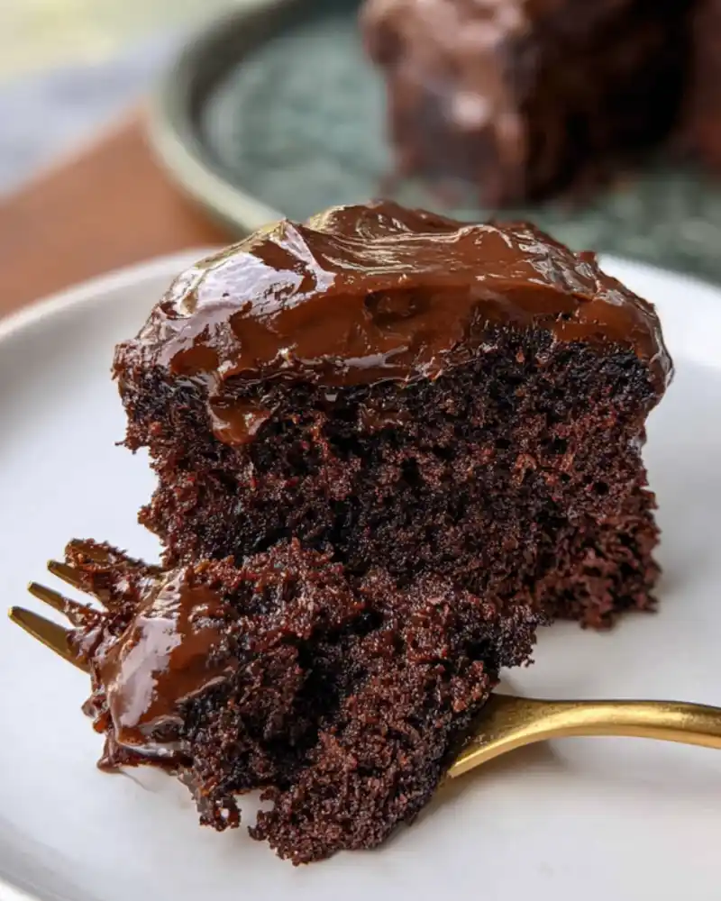 Fork resting in slice of chocolate cake
