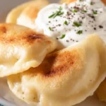 Homemade gluten-free perogies filled with creamy potato and cheese, served with melted butter and sautéed onions on a rustic plate.