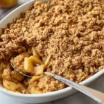 Gluten-free apple crisp in a baking dish with a golden oat topping just out of the oven.