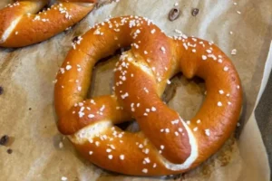 Baked gluten-free Bavarian soft pretzels on a parchment-lined baking sheet, sprinkled with coarse salt.