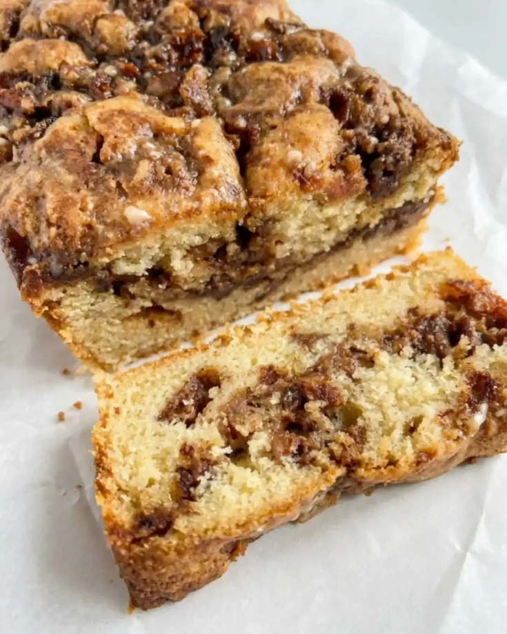 Sliced gluten-free apple fritter loaf with cinnamon apples and maple glaze