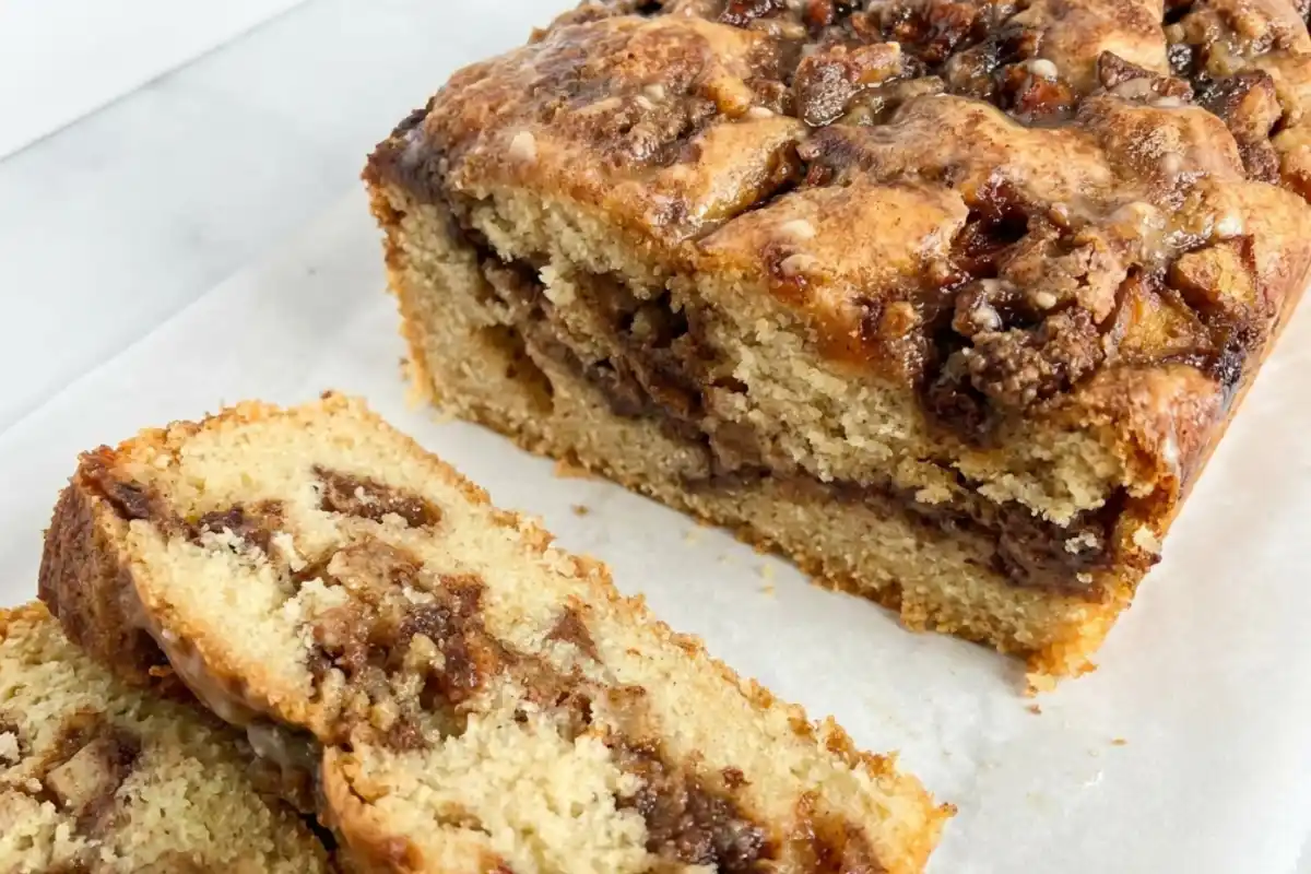 Sliced gluten-free apple fritter loaf with cinnamon apples and maple glaze