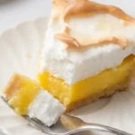Slice of gluten-free lemon meringue pie with tart lemon filling and golden meringue topping