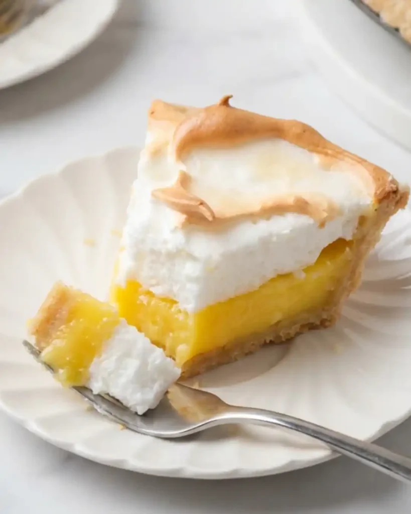 Slice of gluten-free lemon meringue pie with tart lemon filling and golden meringue topping
